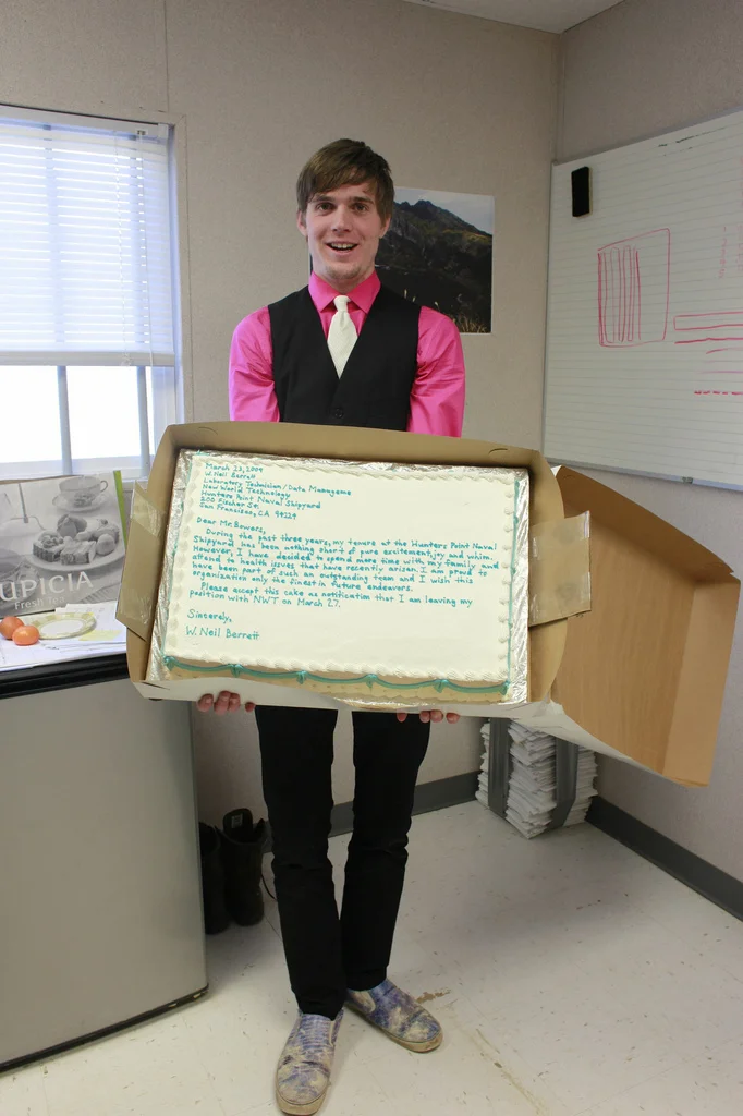 Public Resignation — Full body photo of man holding a resignation cake with letter written in frosting