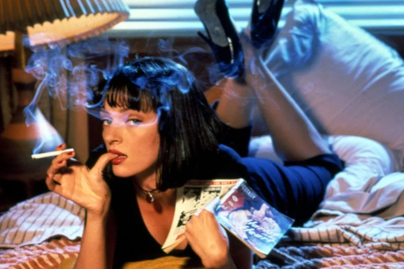 Pulp Fiction — Uma Thurman as Mia Wallace lying on a bed reading a pulp novel while smoking.