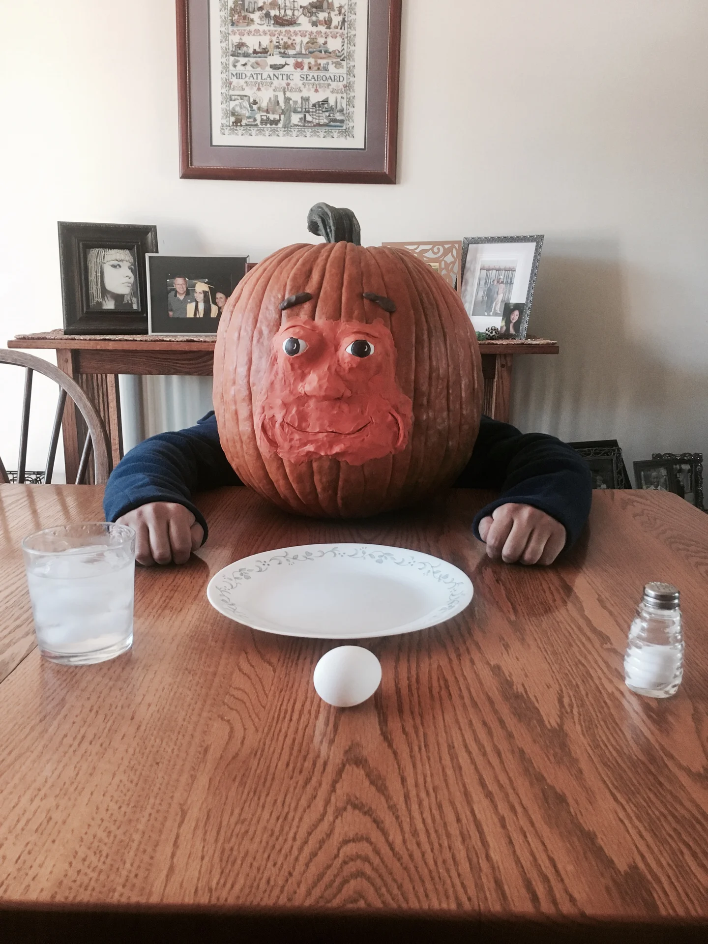 Pumkin — Real pumpkin with sculpted clay face sitting at a table with plate and egg