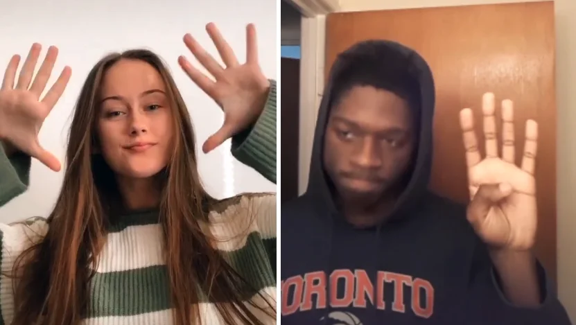 Two people demonstrating the signature hand-raising response gesture of the Put a Finger Down TikTok challenge, showing how participants respond when a