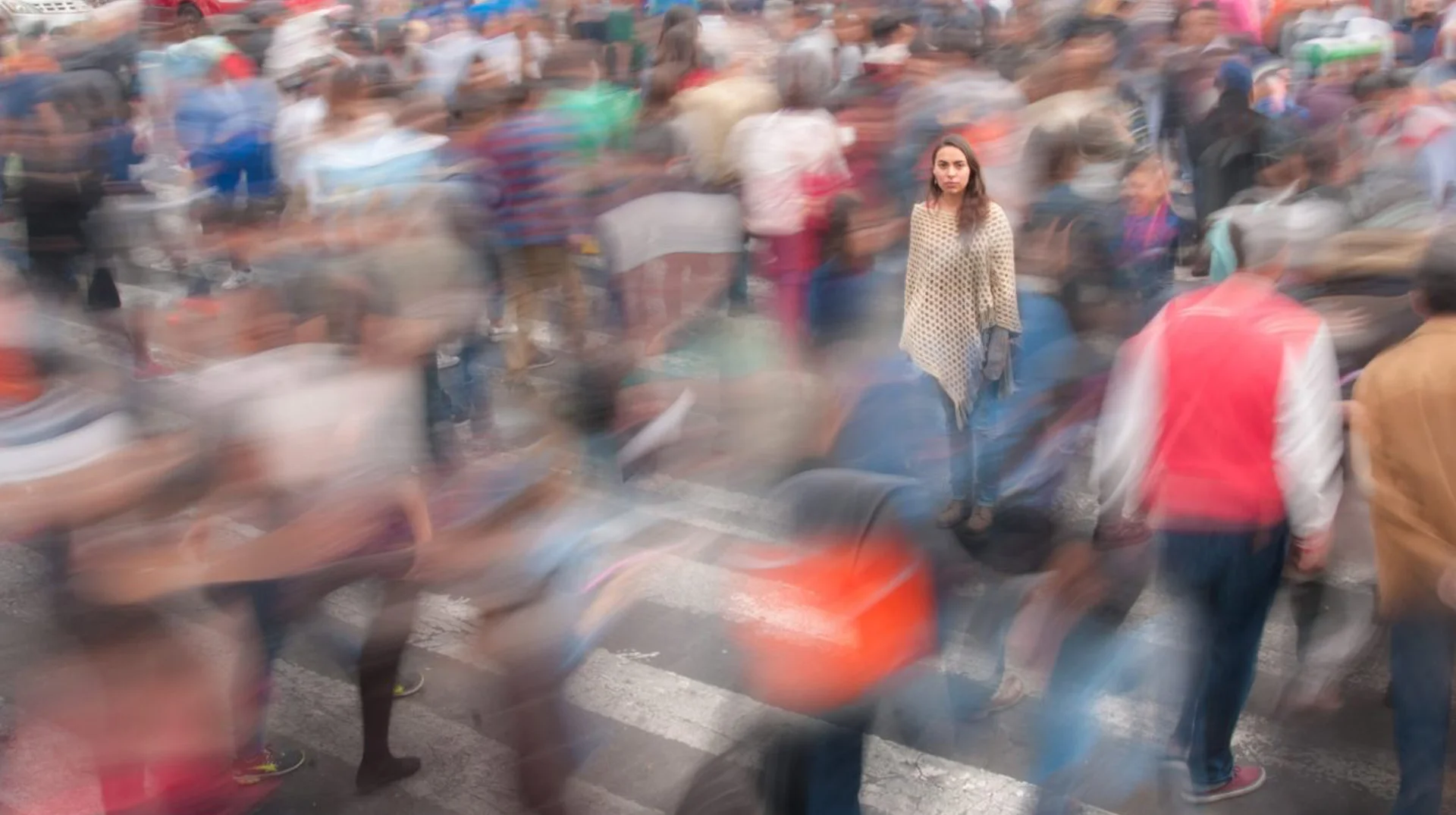 Real Life Npc — Woman standing motionless in the middle of a blurred, moving crowd on a city crosswalk