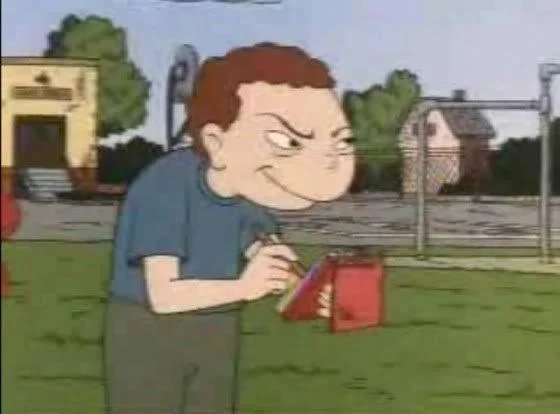 Recess — Cartoon boy on a playground smirking while holding a red handheld device.
