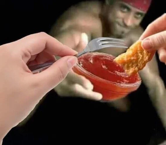 Chicken nugget dipped into ketchup bowl containing Ricardo Milos image