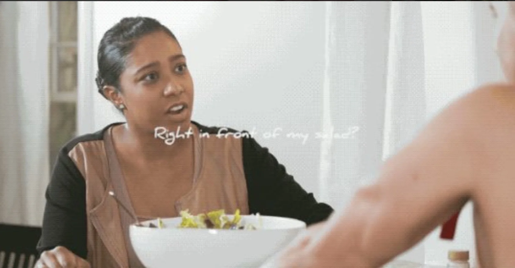 Woman at table with salad bowl looking shocked with caption 'Right in front of my salad?'