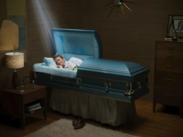 RIP in Peace — Young man lying in a blue open casket in a dark room.