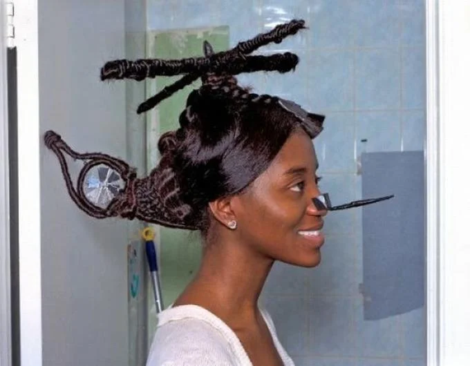 Roflcopter — A side-profile photograph of woman with elaborate hairstyle sculpted to resemble helicopter complete with rotor blades, tail section, and landing