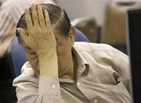 Sad Guys On Trading Floors — A person in light-colored shirt pressing face entirely into raised hand in gesture of complete despair with blurred trading floor