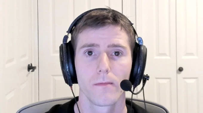 Sad Linus — A clean portrait of Linus Sebastian wearing gaming headphones with microphone boom in home studio against neutral white background.