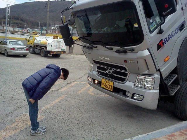 Sad Truck — Young man bowing his head in front of a large silver Hyundai truck outdoors.