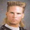A portrait photograph of the young man from the original Safety Not Guaranteed advertisement showing his distinctive mullet hairstyle and casual 1990s style.