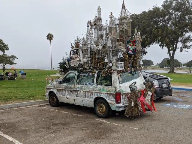 Schizophrenia Rides Schizo Whips — Minivan topped with an elaborate castle-like sculpture of miniature towers and trinkets