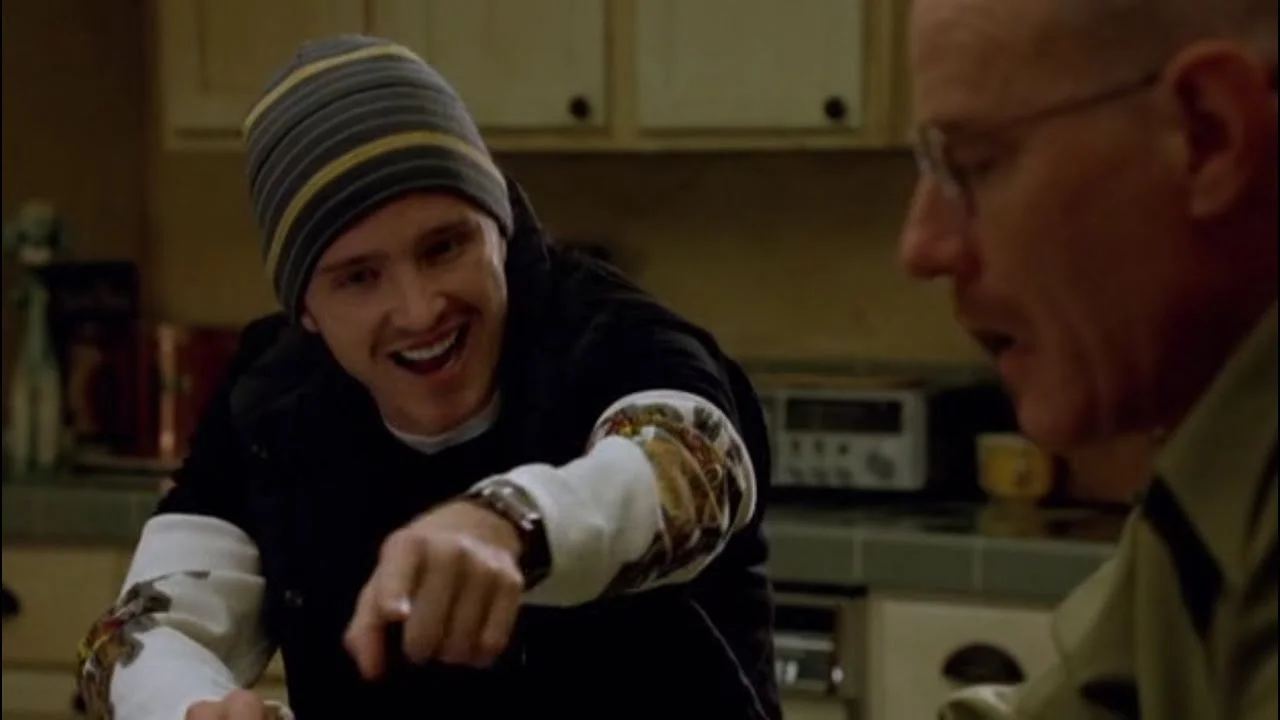 Science Bitch — Unmodified scene from Breaking Bad showing Aaron Paul's Jesse Pinkman in laboratory wearing beanie with enthusiastic expression and hand