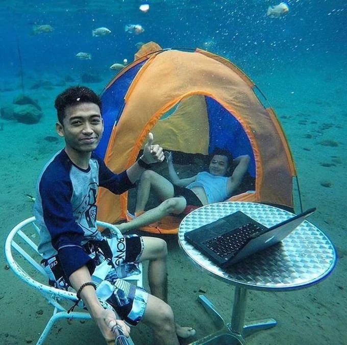 A non-traditional Selfie Olympics variant showing a person taking a selfie while underwater in a tent, extending the trend beyond typical bathroom settings.