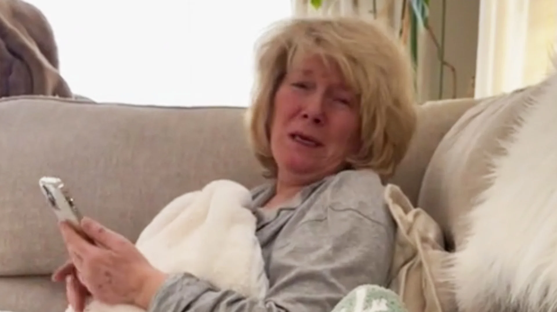 Blonde woman on couch holding phone with emotional expression from Send It to Me Rachel TikTok