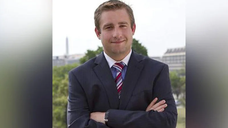 Seth Rich's Death — Portrait of Seth Rich in a suit standing in front of the Washington D.C. skyline