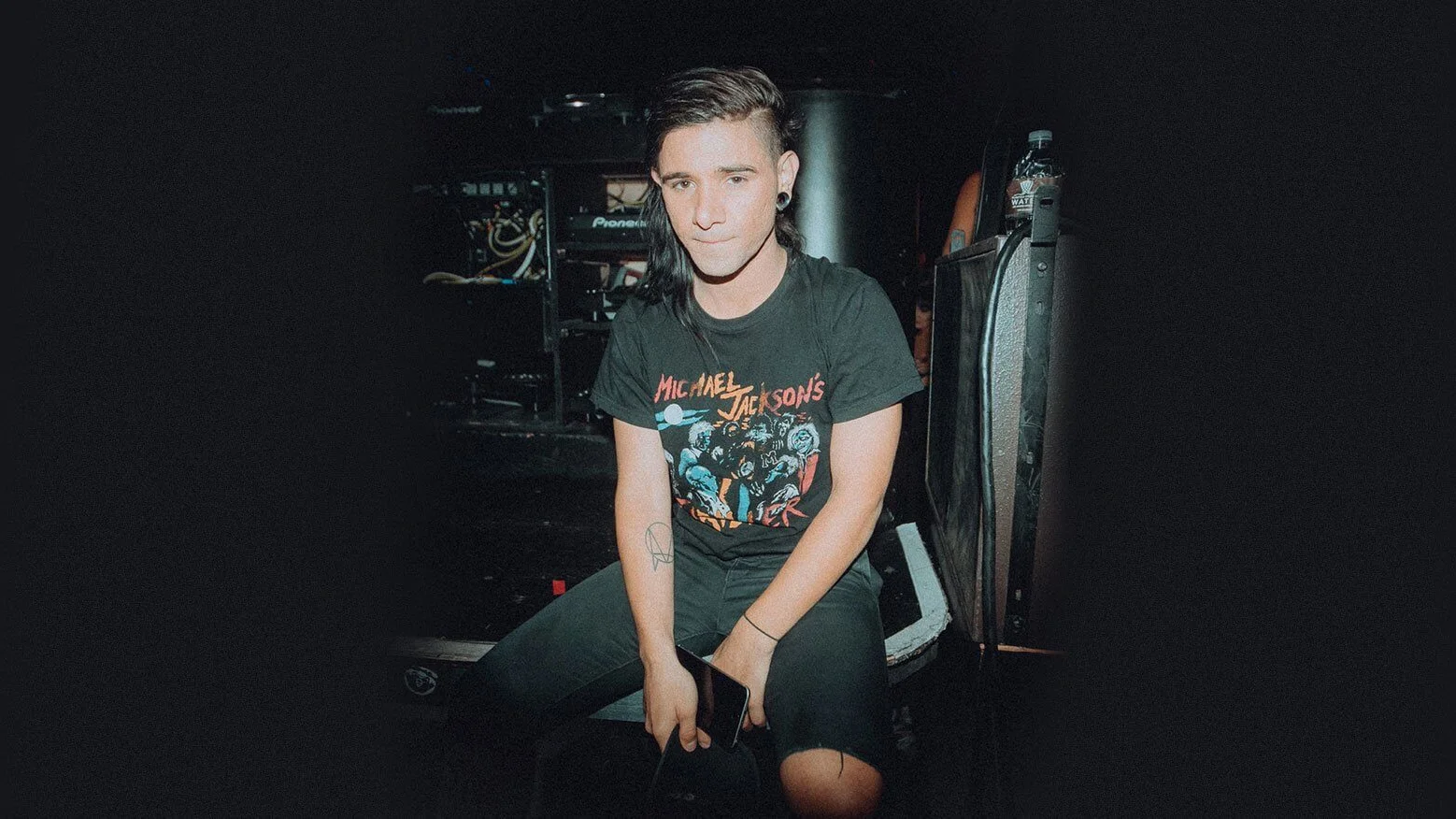 Skrillex sitting backstage wearing a Michael Jackson Thriller shirt
