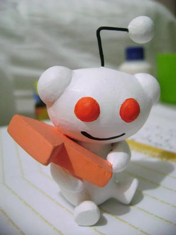 Handmade painted Snoo figurine holding an orange bat