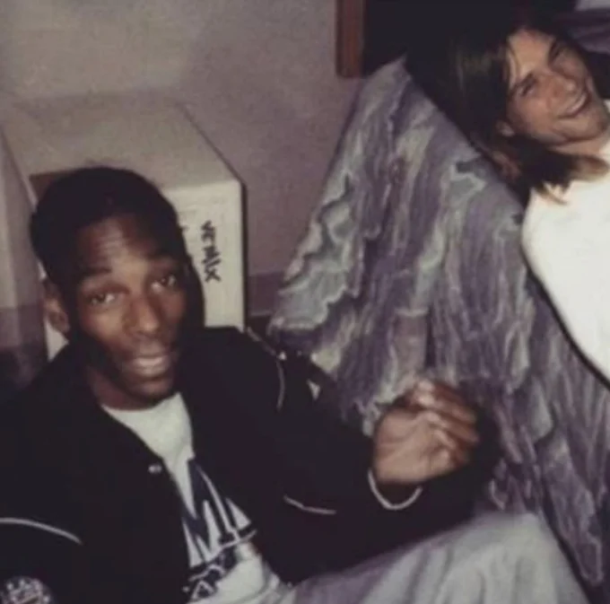 Vintage photograph of a young Snoop Dogg seated next to a long-haired man resembling Kurt Cobain