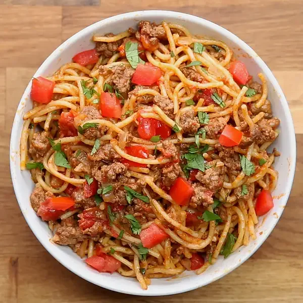 Bowl of spaghetti with tomato sauce, basil, and parmesan cheese