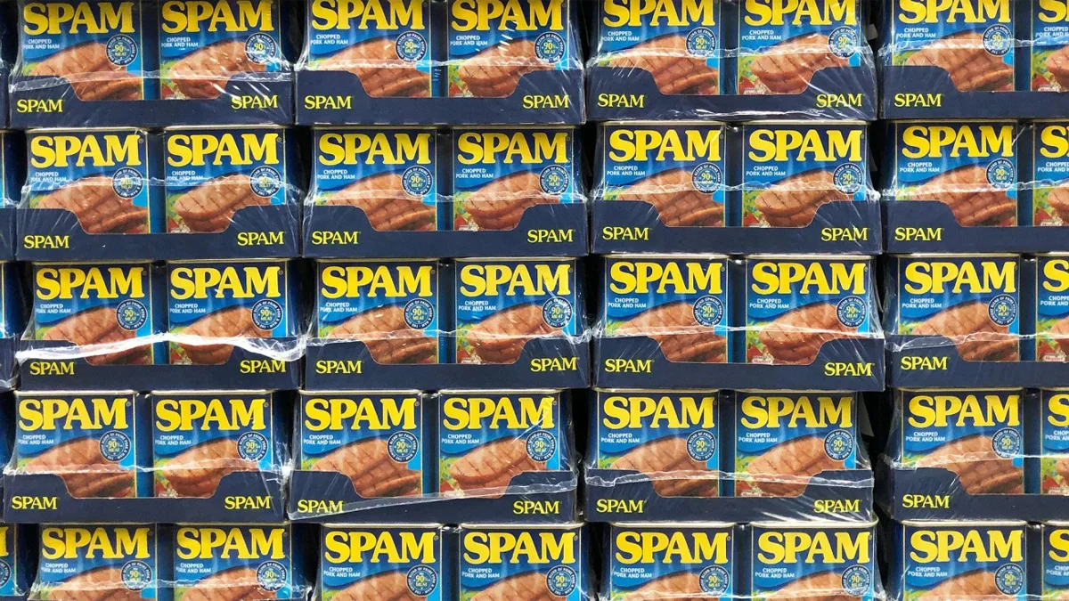 Rows of stacked SPAM canned meat boxes with yellow logo on blue background