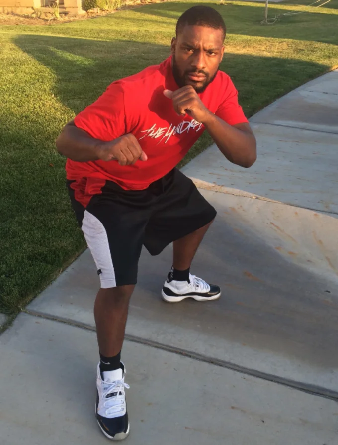 Square Up — Portrait view of man in red shirt in a boxing stance on sidewalk