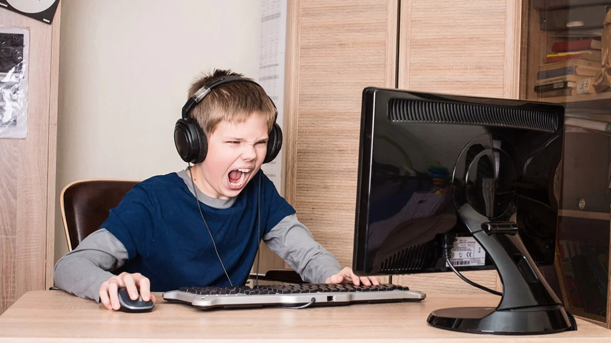 Squeakers — Angry young boy with headphones screaming at a computer monitor while gaming