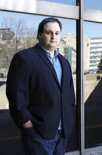 Star Wars Kid — Professional photograph of an adult man in business casual attire standing outdoors near a modern building.