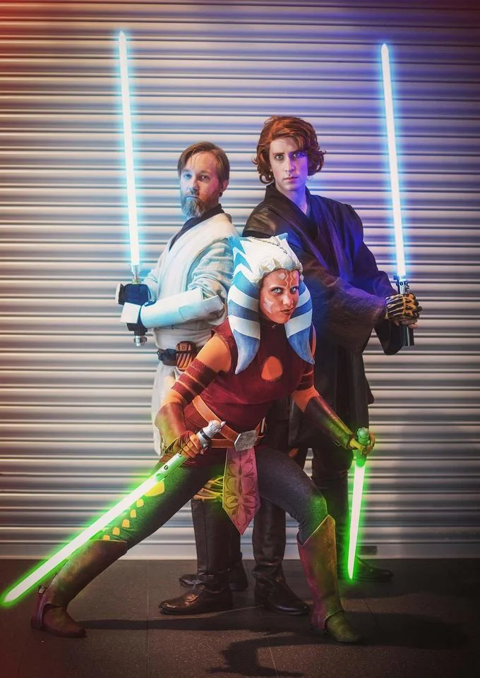 Star Wars: The Clone Wars — Cosplayers of Obi-Wan, Ahsoka, and Anakin posing with lightsabers.