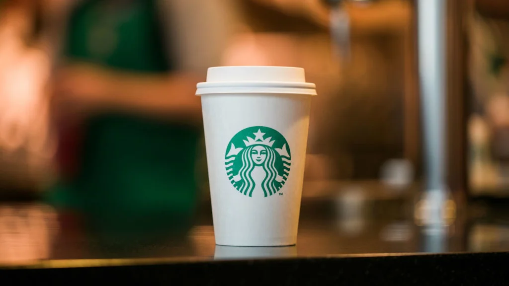 White Starbucks paper coffee cup with green siren logo on a counter