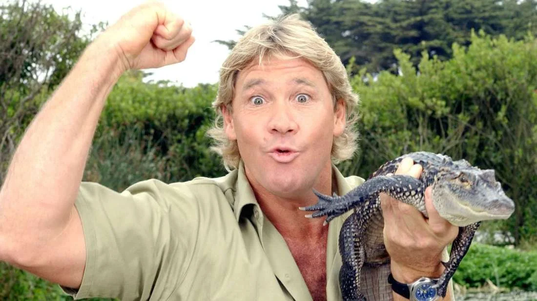 Steve Irwin holding a baby alligator and flexing his arm