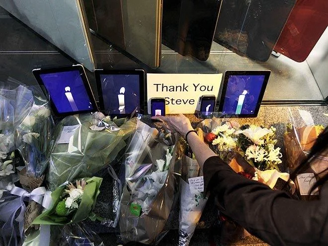 Steve Jobs' Death — Apple Store memorial with iPads showing candles and Thank You Steve sign