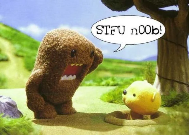 Brown Domo-kun plush character yelling STFU n00b at a small yellow puppet