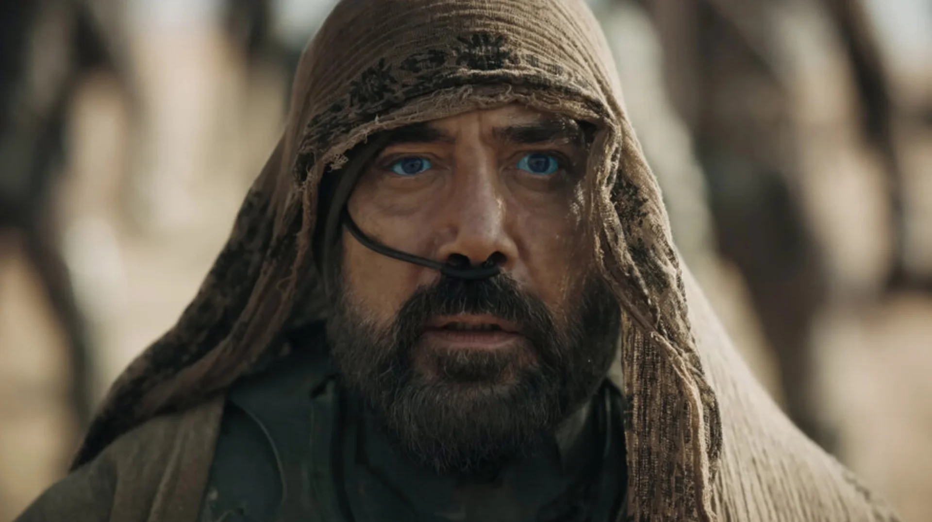 Stilgar (Dune Character) — Close-up of Stilgar from Dune: Part Two wearing a Fremen hood and stillsuit nose tube, with vivid blue eyes.