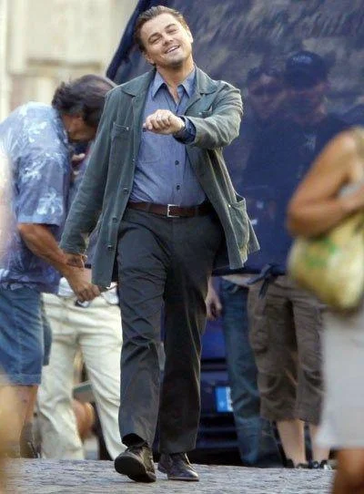 Strutting Leo — Original photo of Leonardo DiCaprio smiling and strutting on a street with crew members around him