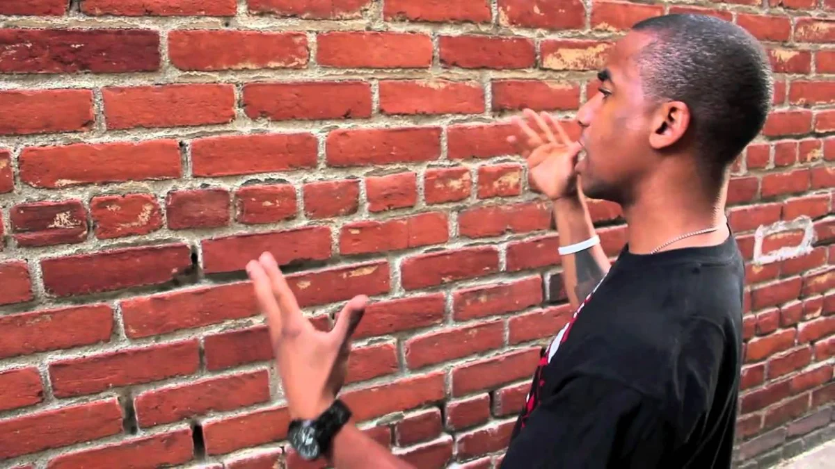 Talking To Brick Wall — Young man in black T-shirt gesturing and shouting at a red brick wall.