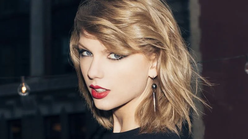 Taylor Swift Eras Tour — Professional headshot of Taylor Swift with blonde hair and red lip makeup.