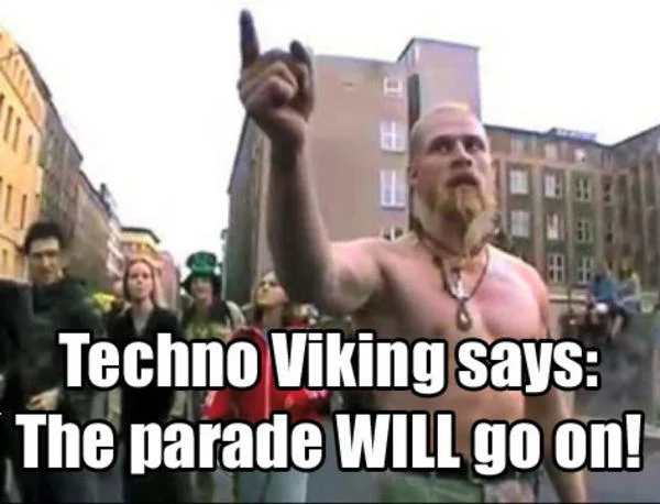 Washed-out still showing Technoviking pointing skyward with crowd and text about parade.