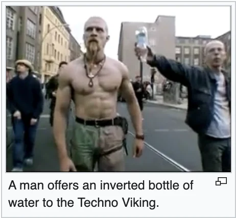 Technoviking — Still frame from original video showing shirtless man with bystander offering inverted water bottle.