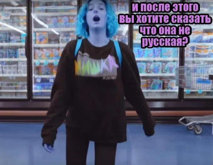 Tessa Violet with blue hair captioned in Russian in front of a freezer aisle