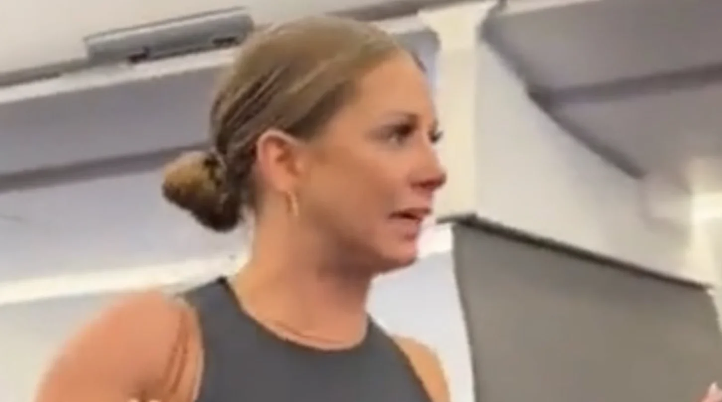 That Motherfucker Is Not Real Plane Woman Tiffany Gomas — Tiffany Gomas in profile view inside an airplane cabin, appearing agitated