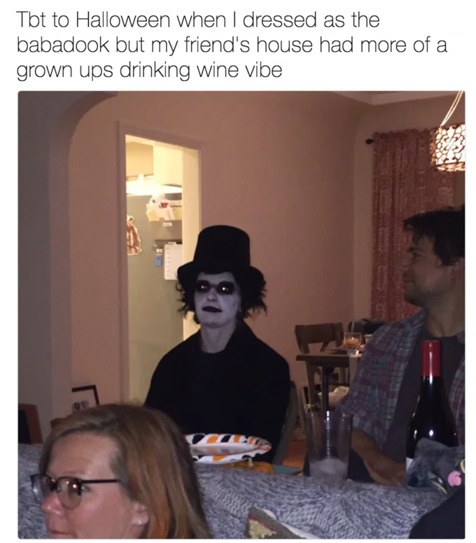 Person dressed as the Babadook sitting at a dinner party captioned about dressing as the Babadook while friends had a wine-drinking vibe