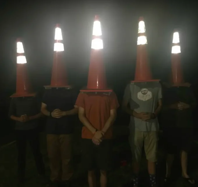 The Council Will Decide Your Fate — Five figures with illuminated traffic cones on their heads at night