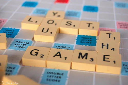 A Scrabble game board with letter tiles arranged to spell 'LOST THE GAME' showing real-world recreation of the meme.