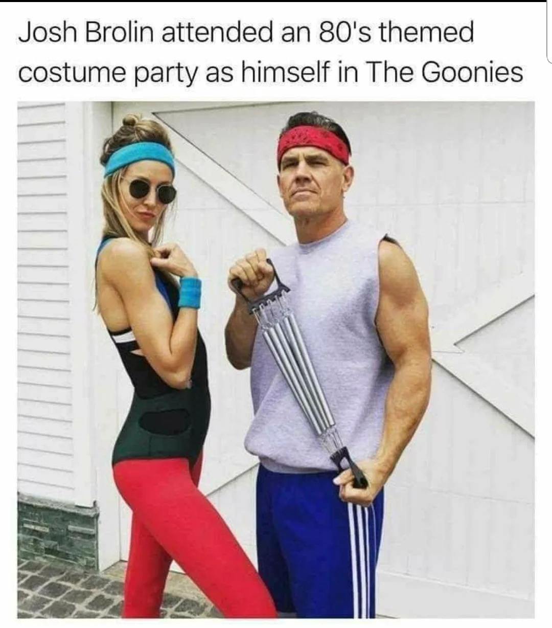 The Goonies — Josh Brolin in 80s workout outfit with headband, holding a chest expander, next to a woman in retro gym attire