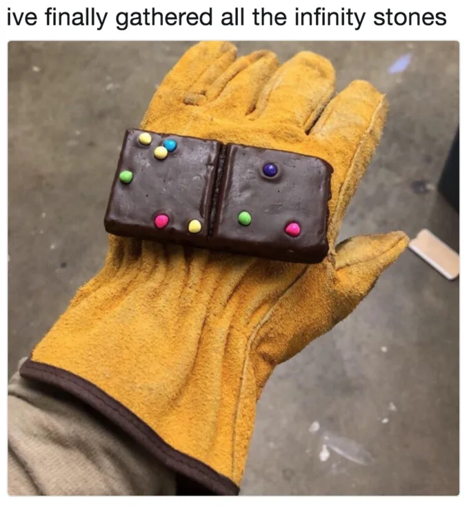 The Infinity Gauntlet — Work glove holding chocolate brownie decorated with candy as infinity stones