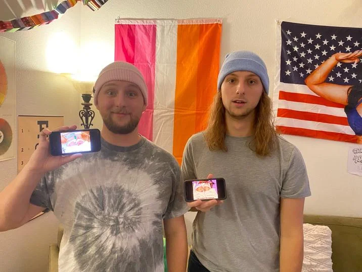 The Ipod Brothers The Fuck You Brothers Sniff And Whimper — Man in NASA cap and tie-dye shirt holding a phone that displays the sniff and whimper twin babies