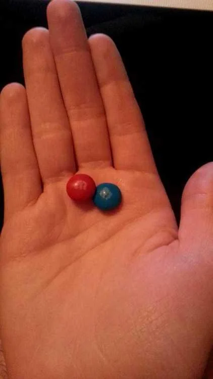 The Matrix — Hand holding a red and blue M&M candy as Matrix pill parody