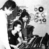 The Most Mysterious Song On The Internet — A small, grainy black-and-white photograph of two individuals at a keyboard or synthesizer workstation in a 1980s