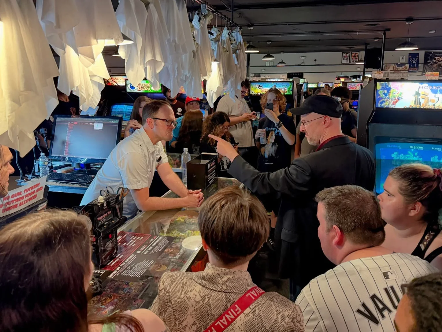 Nostalgia Critic pointing accusingly at an arcade worker in a crowded shop