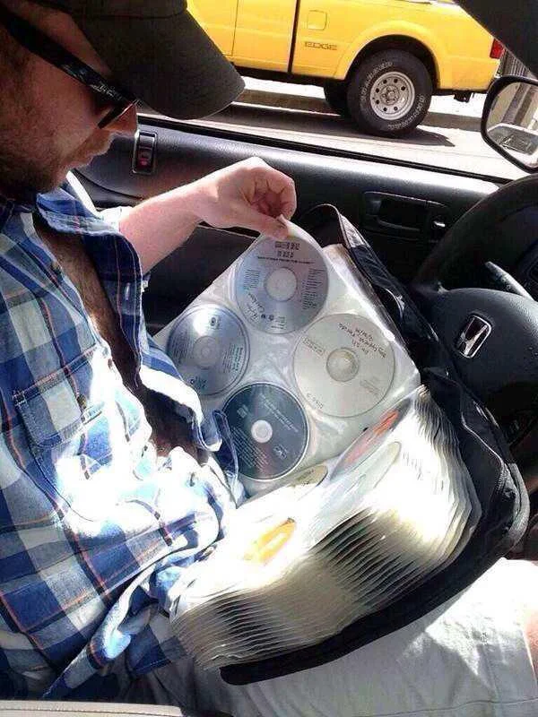The Struggle Is Real — Man in car holding a binder filled with many CDs